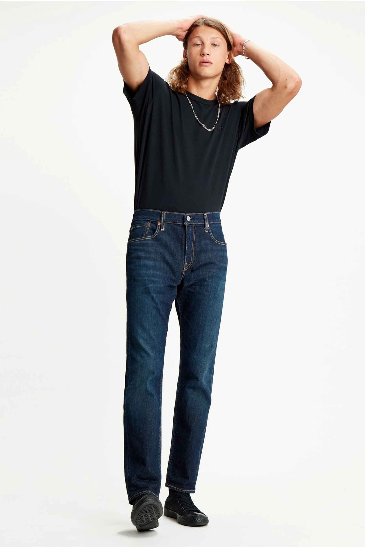 Jean tapered bleu marine de Levi's, porté avec un T-shirt noir et une chaîne d'argent.