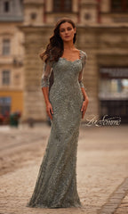 A woman wears the La Femme 31909 long formal dress, featuring a fitted silhouette, lace fabric, three-quarter sleeves, and delicate embroidery as she stands on a cobblestone street.