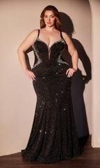 A woman stands with hands on hips in the Ladivine CM365C, a plus-size long black prom dress featuring thin straps and sparkling beads, highlighting the elegance of this stunning formal gown against a light-colored wall.